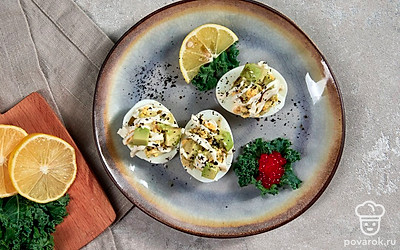 Украсьте каждую половину фаршированного яйца листьями кинзы.