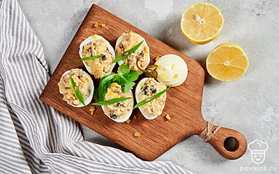 Яйца, фаршированные шампиньонами, положите на красивое сервировочное блюдо и украсьте сверху узором из майонеза.