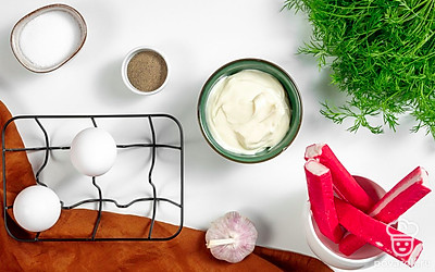 Промойте зелень и обсушите бумажным полотенцем. Листья петрушки отделите от стеблей. Яйца вымойте и отварите вкрутую около 10 минут. После переложите их в прохладную воду для остывания. Разморозьте крабовые палочки, очистите от оберток и поместите в емкость с горячей водой. Через пару минут достаньте их, обсушите и аккуратно разверните. Чеснок промойте и очистите.