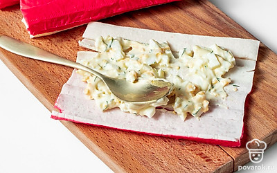 Зафаршируйте крабовые палочки. Промажьте развернутые крабовые палочки полученной начинкой. Плотно сверните их в рулет. Уберите фаршированные крабовые палочки в холодильник на 30 минут.