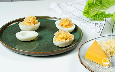 Нафаршируйте яйца. Выложите желтковую массу на половинки яиц. Сверху добавьте майонез с чесноком. Украсьте рубленой зеленью.