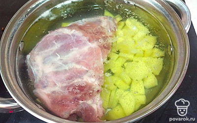 Свиные ребрышки выложите к картошке. Залейте все водой, поставьте на средний огонь, варите 20 минут. 