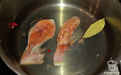В кастрюлю налейте воду, положите два стейка горбуши, лавровый лист, розовый перец, соль. Варите бульон 15-20 минут.
