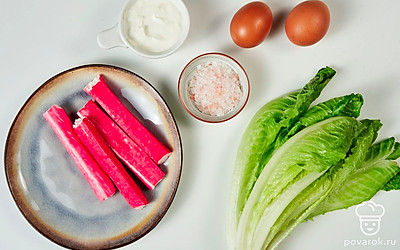 Куриные яйца вымойте, сварите вкрутую, остудите и почистите. Листья салата вымойте и обсушите. Крабовые палочки извлеките из индивидуальной упаковки.