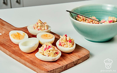 Доведите блюдо до готовности. Разделите начинку на 4 части и разложите по половинкам яиц.