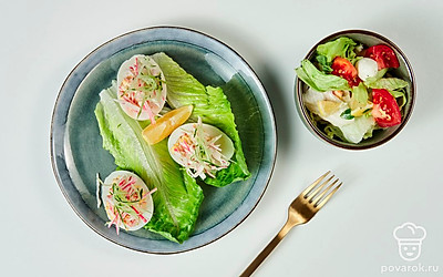 Подайте яйца, фаршированные крабовыми палочками, на сервировочной тарелке, застеленной листьями салата.