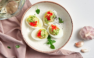 При подаче украсьте фаршированные яйца веточками петрушки.