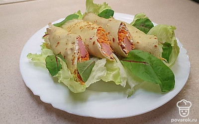 Разрежьте каждую трубочку по диагонали пополам. Большую плоскую тарелку выложите листьями салата айсберг, а сверху разложите половинки начиненного блина, украсьте листьями свеклы или любой другой зеленью.