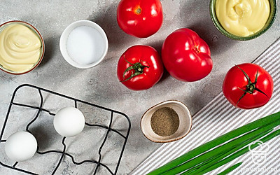 Помидоры ополосните и обсушите бумажными полотенцами. Разрежьте томаты пополам и удалите семена и мякоть. Также срежьте снизу небольшую часть, чтобы закуска устойчиво стояла на тарелке. Зеленый лук помойте, высушите и мелко нарежьте, отложите часть для украшения.