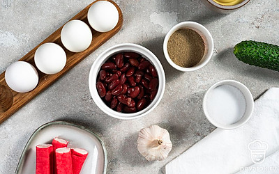 Крабовые палочки освободите от упаковки, порежьте на несколько частей. Чеснок очистите и пропустите через пресс. Морковь ополосните и очистите от грязи, поместите в кастрюлю с водой и варите 20 минут с момента закипания. Затем очистите овощ и фигурной вырубкой вырежьте цветы. Зеленый лук и салатные листья ополосните, высушите бумажными полотенцами, лук мелко порубите.