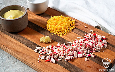 Приготовьте начинку и нафаршируйте яйца. Крабовые палочки и яичные желтки сложите в чашу блендера. Добавьте измельченный чеснок, консервированную фасоль, майонез, соль, перец по вкусу. Пюрируйте ингредиенты до состояния однородного крема. Наполните массой половинки яиц. Для удобства воспользуйтесь кондитерским шприцем.