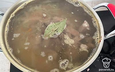 Добавьте нарезанную соломкой капусту и картошку. Достаньте мясо, разрежьте на брусочки и отправьте обратно в бульон. Добавьте соль, перец и лавровый лист. Варите еще 15 минут.