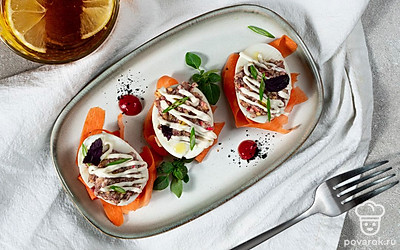 Салатные листья разложите на тарелке, затем на них перенесите фаршированные яйца и украсьте верхушки морковными цветами. Посыпьте закуску зеленым луком.