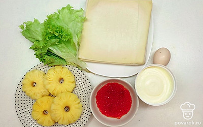 Вытащите с морозилки слоеное тесто, примерно за 20 минут до начала приготовления, с консервированных ананасов слейте сок, листья салата помойте и хорошо обсушите. Подготовьте противень для выпекания и застелите его пергаментной бумагой, приготовьте кисточку для смазывания теста и остальные продукты.