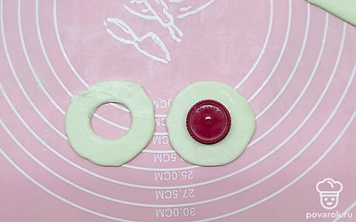 Слегка присыпьте стол мукой и выложите на него размороженное слоеное тесто. Возьмите какую-нибудь выемку и не раскатывая тесто, вырежьте кружки. Теперь, у половины заготовленных кружков, вырежьте серединки, используя водочную крышку. После этого потихоньку вытащите серединки и у Вас получатся кольца.