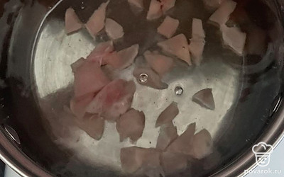 В кастрюлю налейте воду. Отправьте туда нарезанное филе, поставьте на средний огонь.