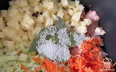 Натрите морковь на мелкой терке. Нарежьте картошку кубиками. Выложите овощи в кастрюлю с капустой и индейкой. Добавьте 1 чайную ложку соли и положите лавровый лист и перец горошком.