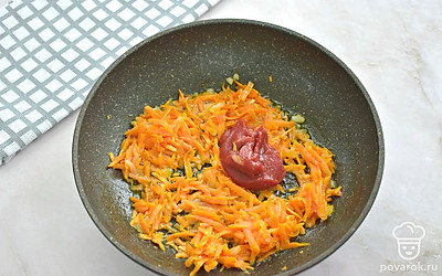 Нагрейте на сковороде растительное масло. Добавьте нарезанный репчатый лук, жарьте его 2 минуты. Затем добавьте тертую морковку, перемешайте. Продолжайте жарить 3 минут. К овощам добавьте томатную пасту, влейте 3 столовых ложки бульона из кастрюли. Тушите 3 минуты.