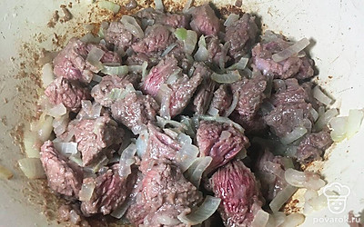 Лук нарежьте полукольцами и обжарьте в казане. Добавьте мясо и обжарьте всё на сильном огне, помешивая.