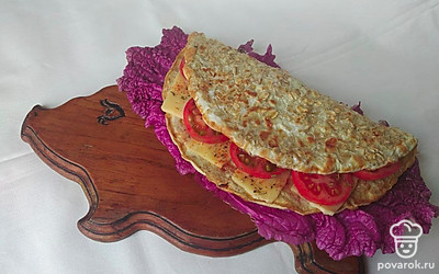 Выложите готовый овсяноблин на лист пекинской капусты. Посыпьте блюдо свежей зеленью и нарежьте помидоры и огурцы. По желанию намажьте сверху творожный сыр.