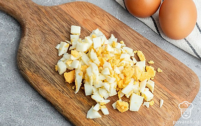 Очистите и нарежьте куриное яйцо, нарубите крабовые палочки.