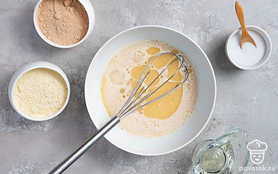 Приготовьте тесто. В глубокую миску высыпьте кукурузную и гречневую муку. Добавьте к ним сахар, соль и вбейте яйца. Перемешайте, чтобы не было комочков. Далее положите в тесто сметану, еще раз перемешайте. Затем в получившуюся массу постепенно влейте кипяток, постоянно помешивая. Добавьте в тесто растительное масло, соду и тщательно размешайте.