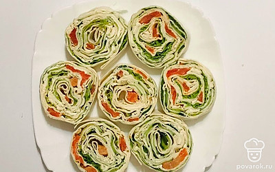 После достаньте из холодильника готовый рулет и нарежьте его с помощью острого ножа порционными кусочками. Красиво сервируйте на подготовленном блюде.