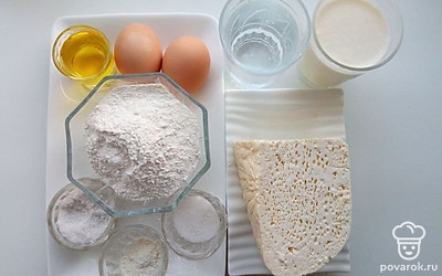 Муку насыпьте в миску. Молоко и воду налейте в стакан. Соль, сахар и разрыхлитель насыпьте в тары. Яйца положите на стол. Растительное масло налейте в стакан. Сулугуни положите на тарелку.