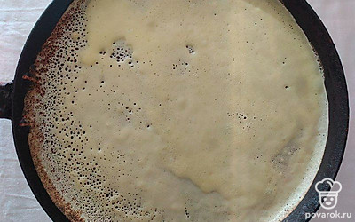 Блинную сковороду смажьте растительным маслом. Вылейте тесто с помощью половника в центр сковороды и жарьте блин по 2 минуты с каждой стороны. Смажьте блин сыром, выложите нарезанную рыбу и немного икры. Заверните трубочкой и аккуратно нарежьте.