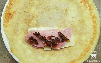 Нарежьте ветчину и сыр тонкими ломтиками, а вяленые помидоры кусочками. Положите на блин несколько кусочков ветчины и сыра, добавьте немного вяленых помидор и заверните конвертом. Поджарьте готовые блины на сливочном масле на медленном огне под крышкой до золотистой хрустящей корочки и сразу подавайте на стол вместе с соусом.