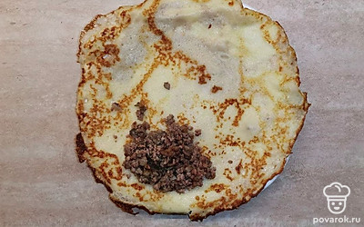 Возьмите плоскую тару и разместите блин на ее поверхности. На край блина положите начинку, заверните края с двух сторон, скатайте трубочкой.