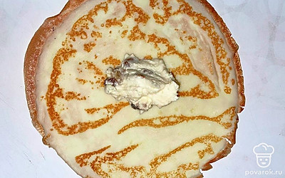 На готовые блины выложите начинку из творога и изюма столовой ложкой.