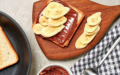 Соберите тост с шоколадной пастой. Возьмите один ломтик поджаренного хлеба, смажьте его шоколадно-ореховой пастой, выложите на нее кружочки бананов и накройте вторым ломтиком хлеба.