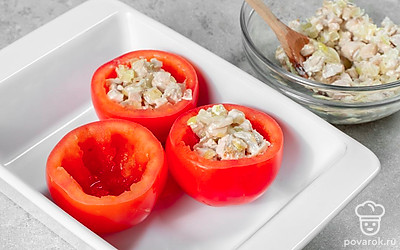 Приготовьте закуску. У помидоров срежьте верхушки, извлеките мякоть. После этого нафаршируйте овощи готовой начинкой. Накройте помидоры верхушками и уберите в холодильник на 10-15 минут, чтобы они настоялись.