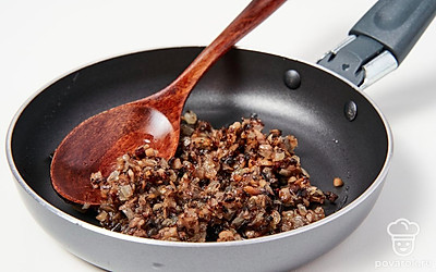 Начните приготовление начинки. Сковороду поместите на средний огонь, влейте растительное масло и оставьте разогреваться. В это же время нарежьте грибы мелкими кубиками, а лук измельчите. Затем выложите на разогретое масло лук, обжарьте его до золотистого цвета. После этого добавьте шампиньоны и специи по вкусу. Готовьте начинку 10-12 минут, постоянно помешивая.