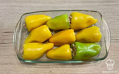 В сковороду добавьте отваренный рис и тщательно перемешайте. Содержимым сковороды начините перцы. Уложите фаршированный перец в жаропрочную посуду.