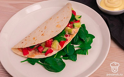 Смажьте соусом лепешку, выложите сосиску, овощи и шпинат. Накройте второй половиной лепешки. Приятного аппетита!