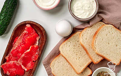 Филе лосося нарежьте тонкими ломтиками. Помойте огурец и натрите его на мелкой терке. Яйца помойте, сварите вкрутую, очистите. Одно нарежьте тонкими кружочками, второе разрежьте пополам. Помойте и обсушите салатные листья.