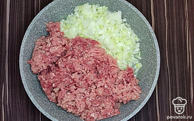 В сковороду влейте масло и выложите фарш. Лук нарежьте кубиками среднего размера и добавьте в сковороду. Перемешайте и тушите на медленном огне на сковороде в течение 10-15 минут.