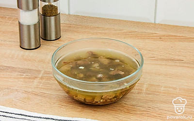 Кусочки мяса сложите в блюдо, посыпьте чесноком и залейте бульоном.