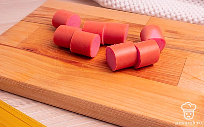 Нарежьте сосиски на кусочки шириной 2-2,5 см.