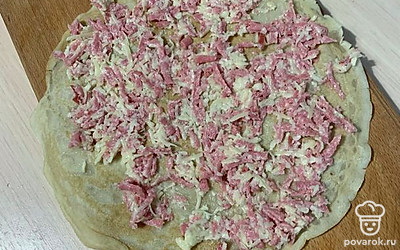 Нашу начинку из колбасы и сыр распределяем по блину.