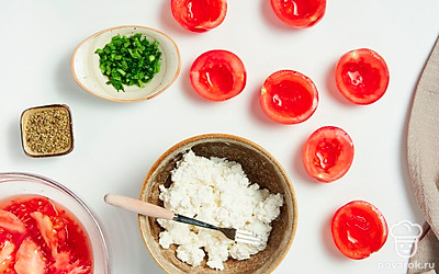 Подготовьте продукты. Срежьте у помидоров верхушку с плодоножкой, достаньте ложкой мякоть. Вилкой измельчите фету. Мелко нашинкуйте зеленый лук.