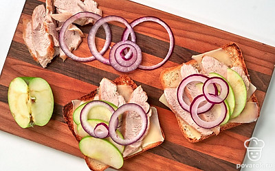 Сделайте тосты. Подсушите хлеб на сковороде или в тостере. Выложите на хлеб сыр, затем индейку. Сверху положите яблочные дольки. Добавьте кольца красного лука.