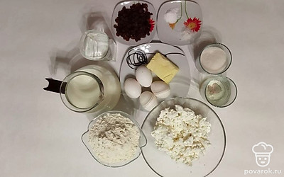 Налейте воду и молоко в стаканы. Выложите творог и муку в тарелки. Промойте изюм и отрежьте масло. Подготовьте соль, сахар, соду, ванильный сахар, масло и яйца.