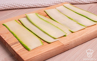 Нарежьте кабачок тонкими длинными слайсами, предварительно очистите кабачок от кожуры.