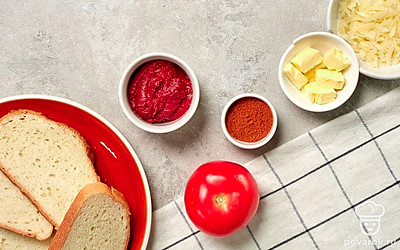 Подготовьте хлеб, томатную пасту, сливочное масло и перец. Помидор помойте и мелко порежьте. Базилик помойте и отделите листочки от веточки. Подготовьте противень и разогрейте духовку до 180 градусов.