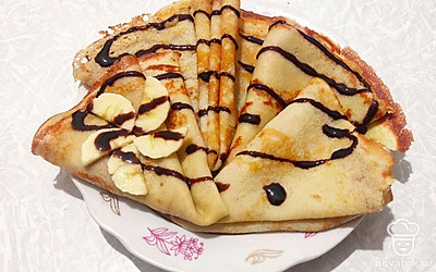 Блинчики украсьте шоколадной глазурью и подайте теплыми к столу с теплым напитком.