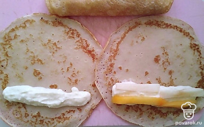 На готовые блины выложите немного начинки. Очистите яблоки от кожуры и порежьте их и хурму соломкой. Выложите немного фрукты на творог и заверните блины.