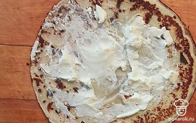 Обжарьте блинное тесто на раскаленной сковороде, вливая его тонким слоем на всю ее поверхность. Поджарьте блинчики с обеих сторон до румяности. После на готовые блинчики выкладывайте ложку сливочного сыра, распределяя его по всей поверхности. Сверните каждый блин трубочкой и нарежьте кусочками. На каждый такой выложите чайную ложку икры.